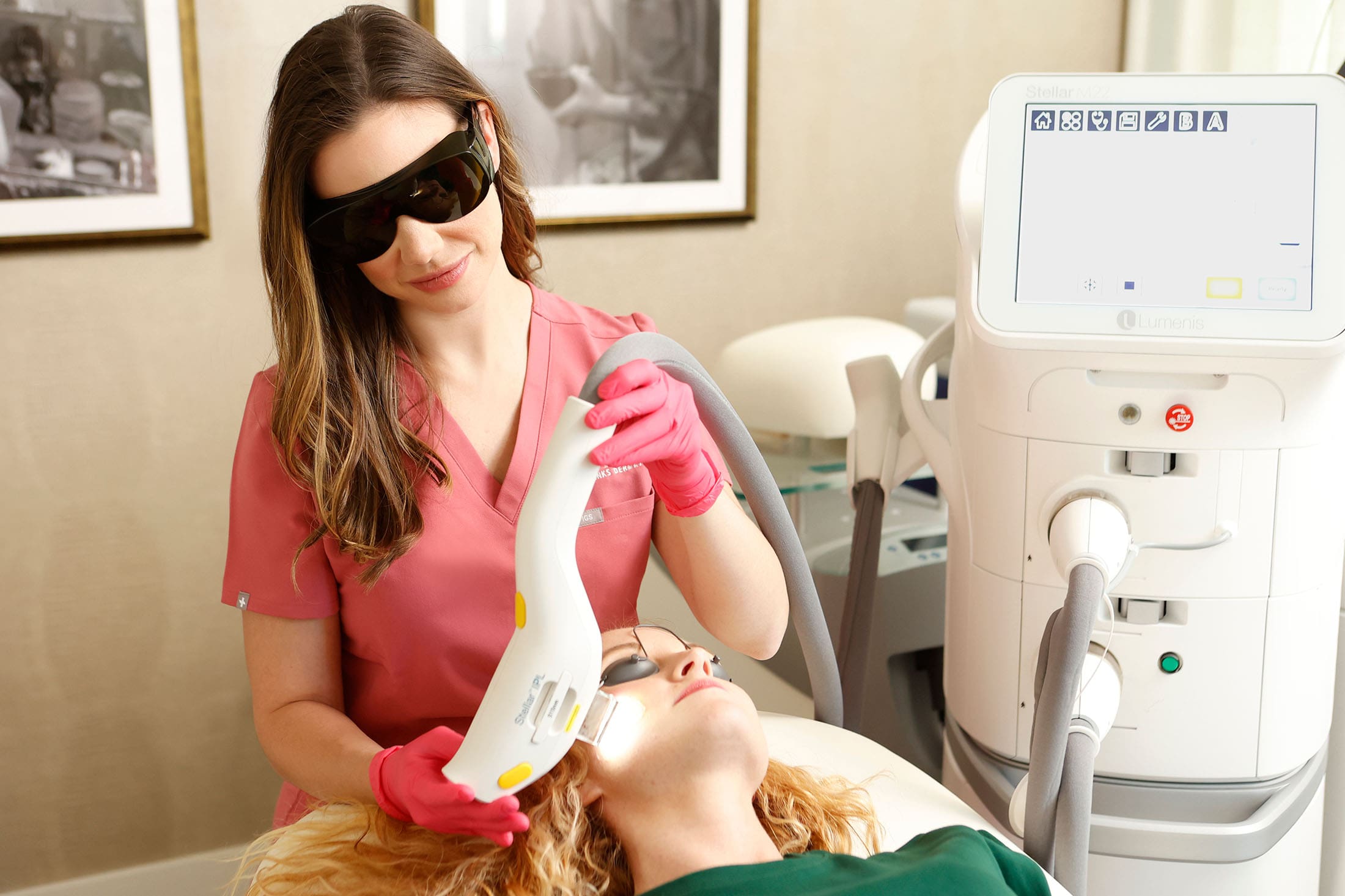 Lindsey smiling and wearing protective glasses while performing a laser IPL photofractional treatment on a patient