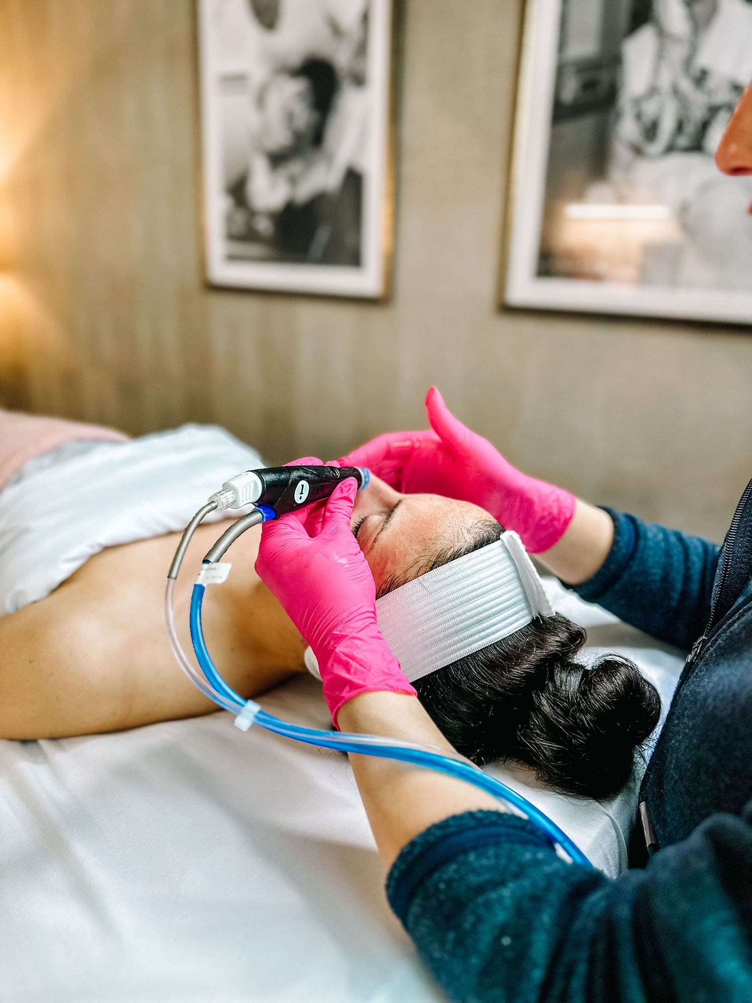 Relaxed woman lying down on a spa table while receiving a hydrafacial treatment