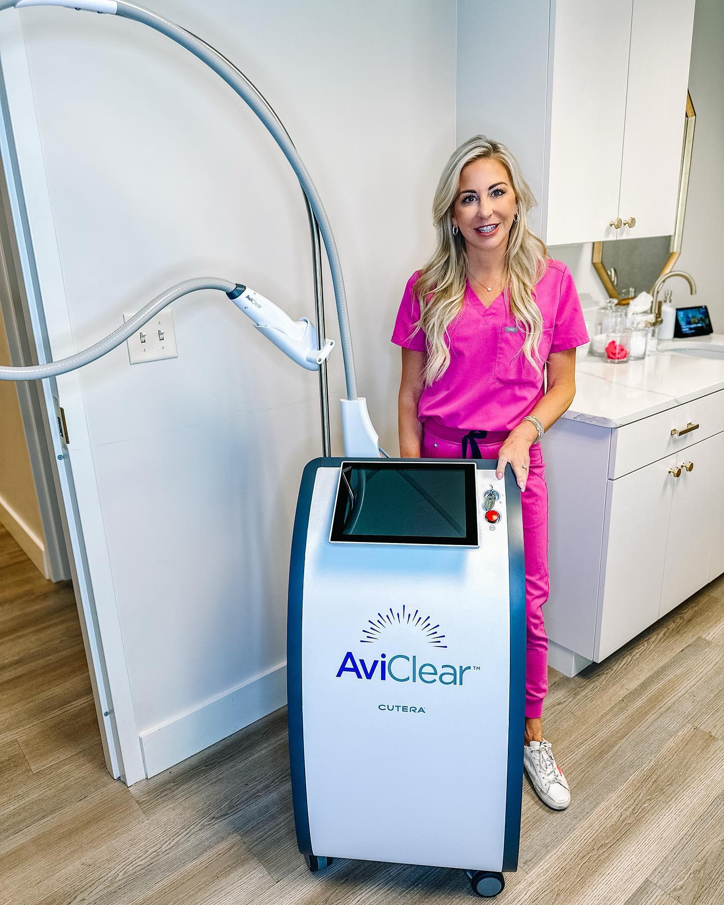 Rachel standing in treatment room with an AviClear machine