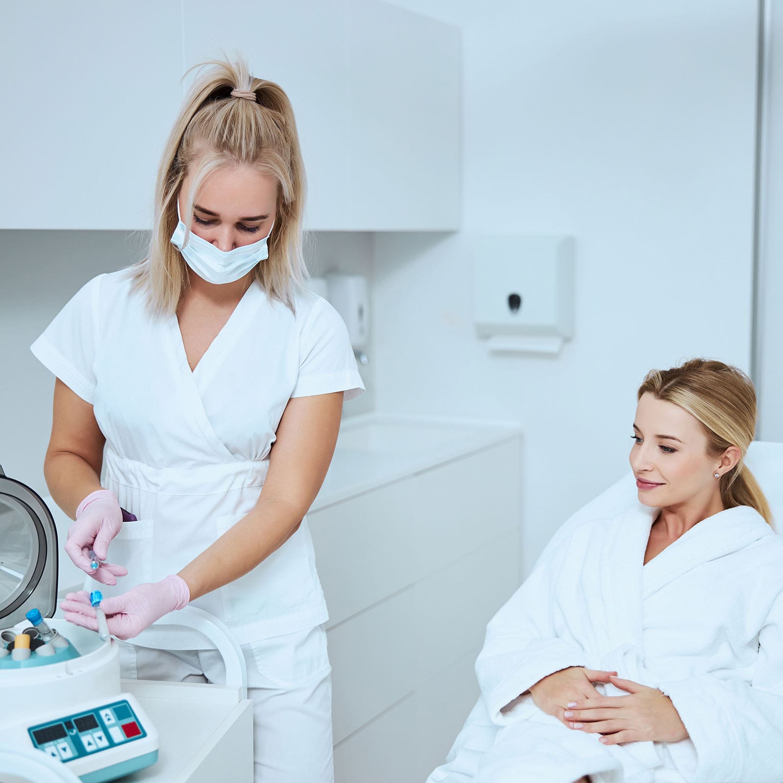 Aesthetician getting ready for a platelet-rich plasma injection as patient looks on