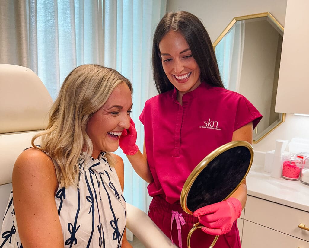 Katie holding a mirror, showing a smiling patient the results of her treatment